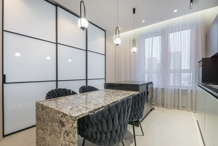 elegante küche mit natursteininsel und designstühlen