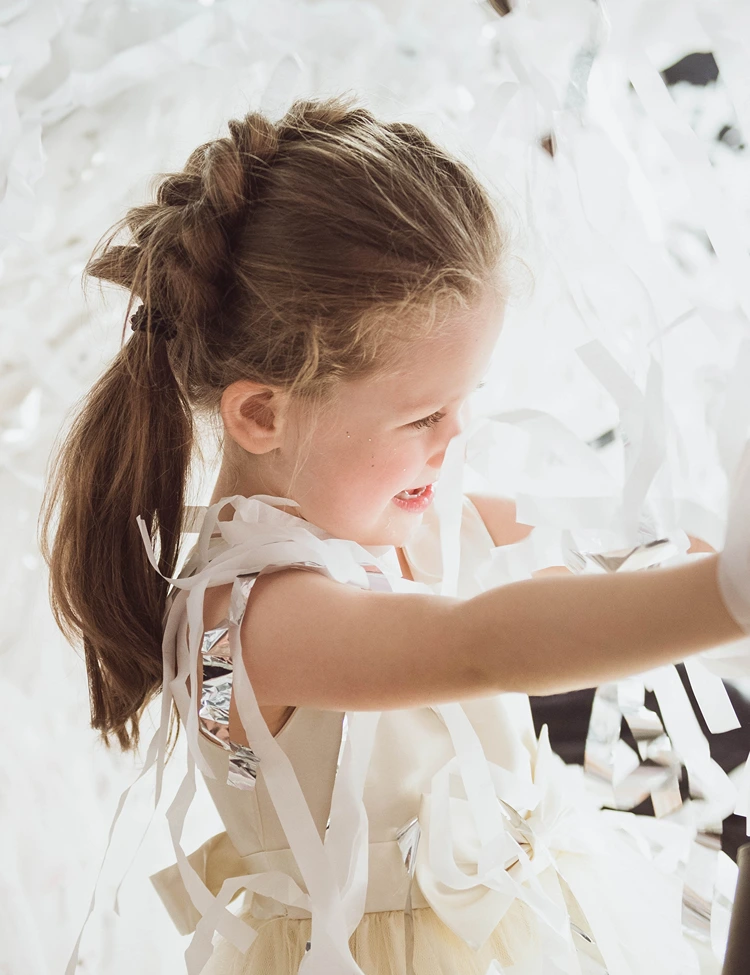 fröhliches geburtstagskind mit dutch braid spielt mit papierstreifen