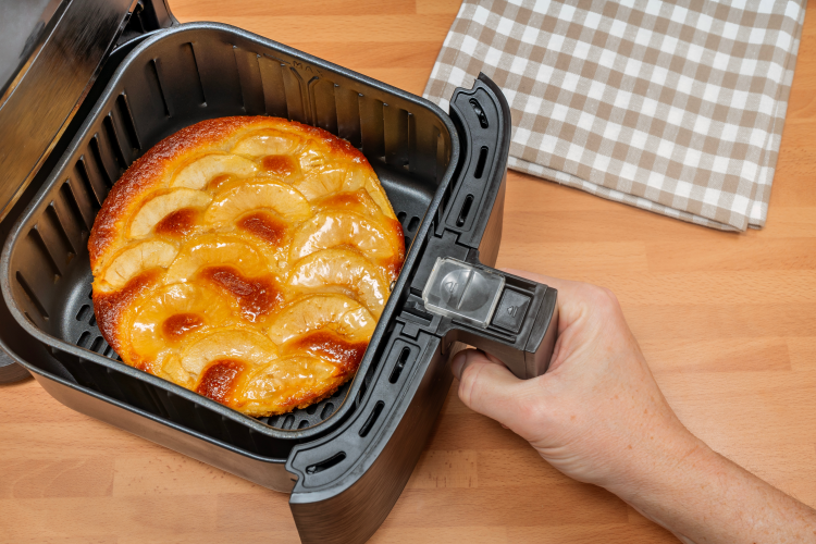 hand hält frisch gebackenen hausgemachten apfelkuchen in einer heißluftfritteuse