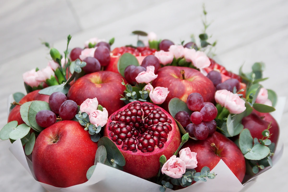 Herbststrauß mit Obst - Trauben, rote Äpfel und Granatapfel bilden ein schönes Farbschema