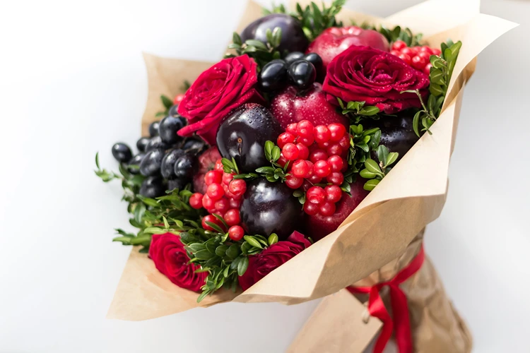 Lecker und romantisch mit Rosen, Pflaumen, Weintrauben und Beeren