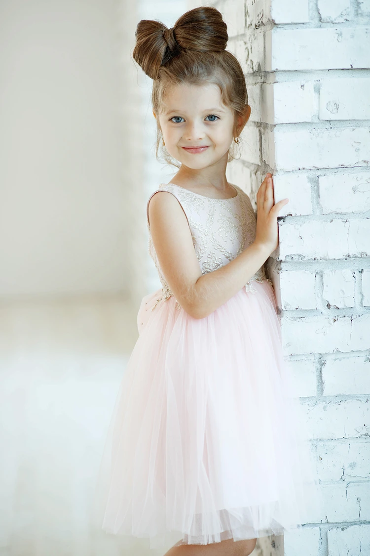 mädchen mit hochsteckfrisur in form einer schleife und rosa tüllkleid – elegante kinderfrisur für hochzeit oder geburtstag