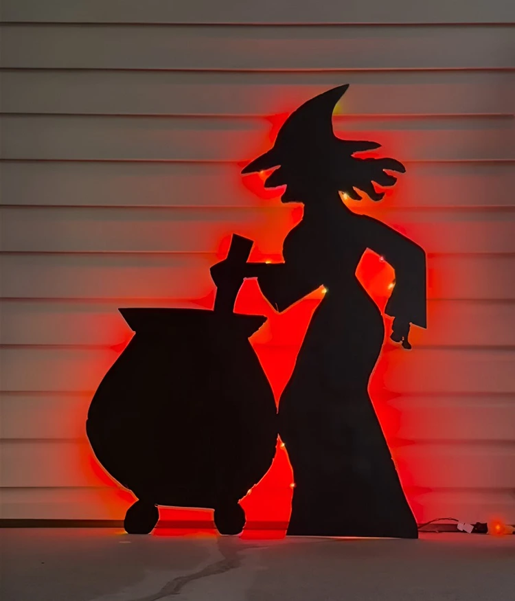 Rot beleuchtete Hexensilhouette aus Sperrholz für den Vorgarten