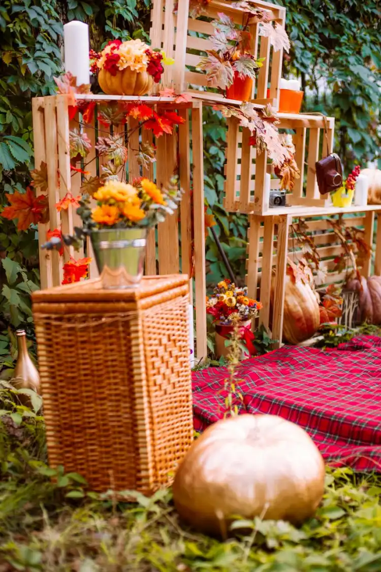 rustikale Herbstdeko mit Zierkürbissen und Herbstblumen und Picknickdecke