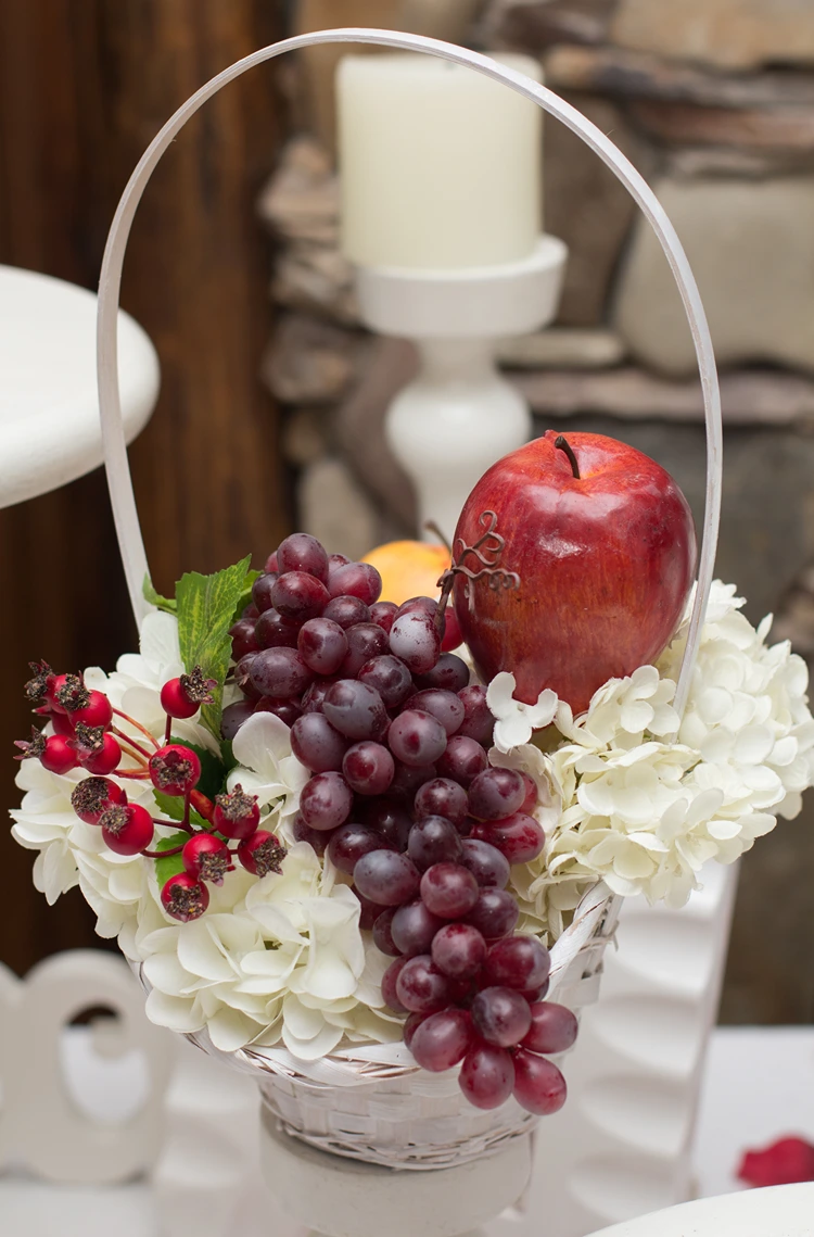 Schönes Herbstgesteck mit weißen Hortensien, Apfel, Hagebutten und roten Weintrauben