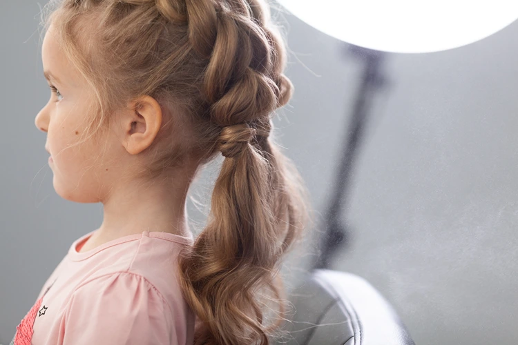 seitenansicht eines mädchens mit zwei zöpfe frisur im pull through stil