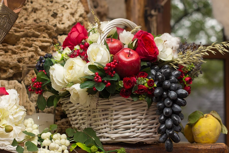 Selbstgemachter Geschenkkorb mit weißen und roten Rosen, Trauben und Äpfeln