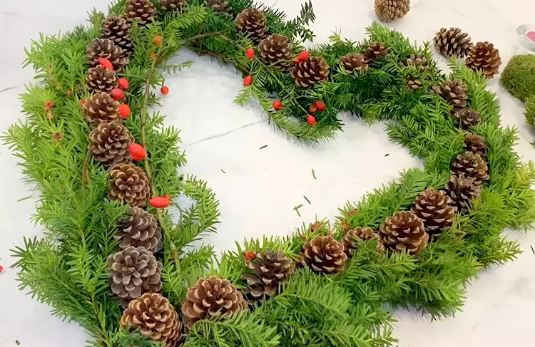 Zweige mit Hagebutte als Akzent rund um das Herz anlegen und festbinden
