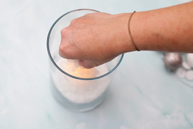 der kleine leuchtende tannenbaum wird mittig in den kunstschnee gesetzt