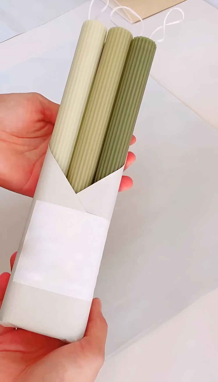 Gekaufte oder selbstgemachte Tafelkerzen hübsch in Papier einwickeln