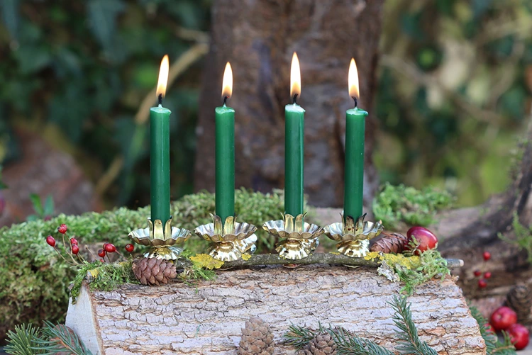 Goldene Kerzenhalter auf einen Holzscheit stecken und mit Grün dekorieren