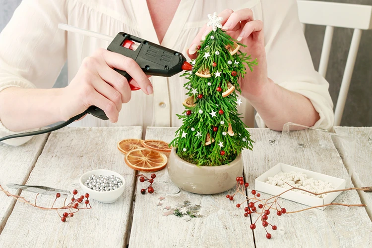 Mit Heißkleber kann Weihnachtsdeko ans Bäumchen geklebt werden