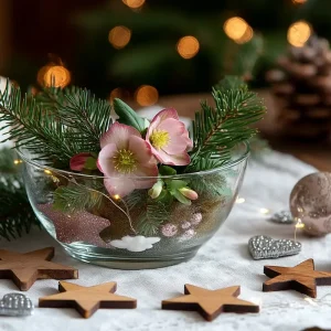 rosafarbene christrose in flacher glasschale mit tannengrün und kleinen weihnachtssternen