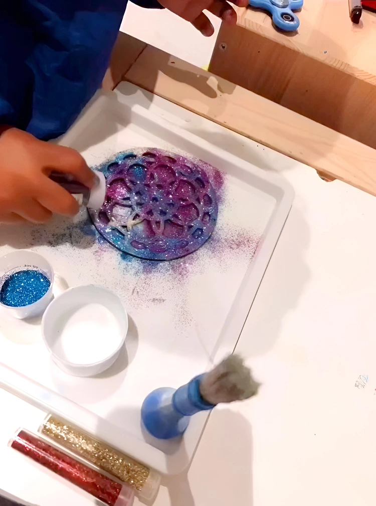 Kleber auftragen und Holzmotiv mit farbigem Glitzer bestreuen